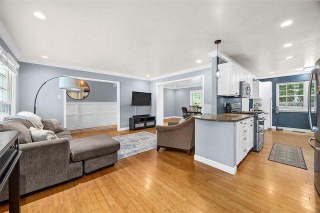 kitchen with appliances with stainless steel finishes, white cabinets, open floor plan, recessed lighting, and light wood-style flooring