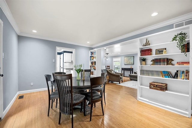 dining room with light wood finished floors, baseboards, ornamental molding, and recessed lighting
