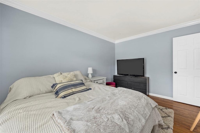bedroom with ornamental molding, wood finished floors, and baseboards