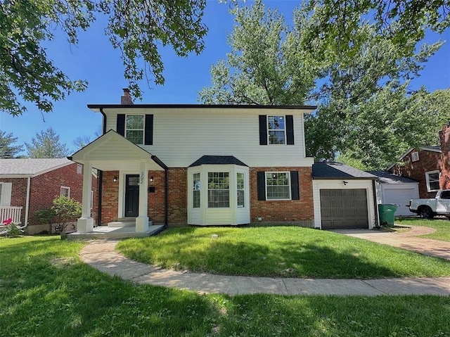 view of front of home featuring a chimney, a front yard, an attached garage, brick siding, and driveway