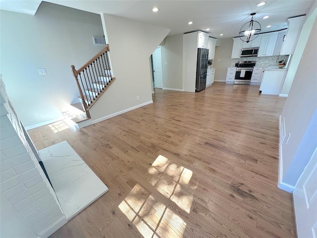 unfurnished living room featuring light wood-style floors, recessed lighting, stairs, and baseboards