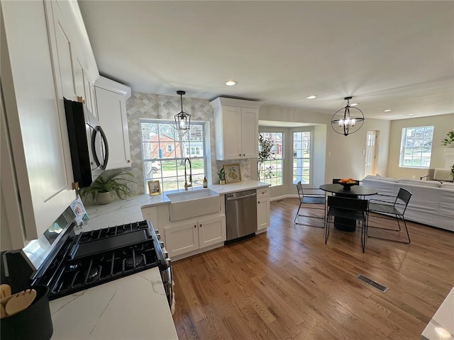 kitchen featuring stainless steel appliances, a sink, white cabinetry, light wood-style flooring, and recessed lighting