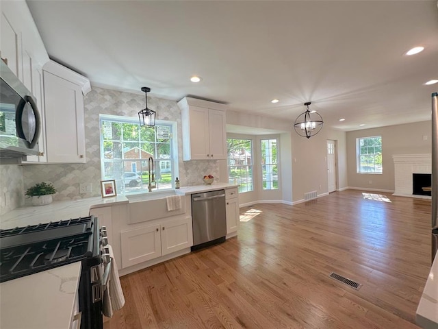 kitchen with stainless steel appliances, a sink, white cabinetry, recessed lighting, and open floor plan