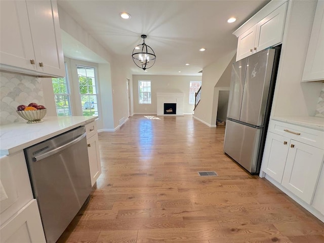 kitchen featuring appliances with stainless steel finishes, backsplash, recessed lighting, light wood-style flooring, and white cabinets