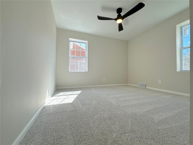 carpeted spare room featuring a ceiling fan and baseboards