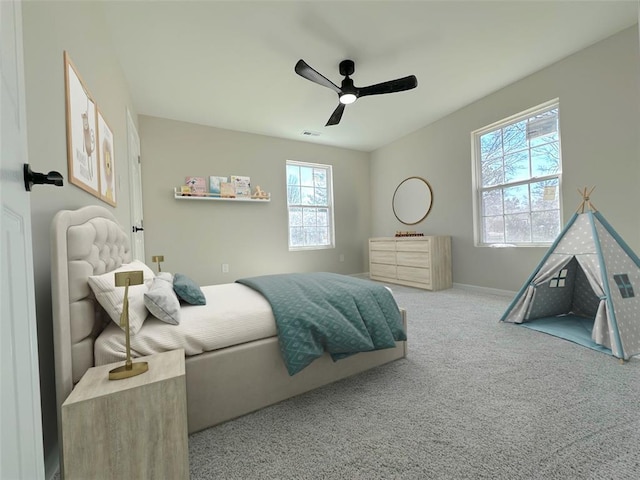 carpeted bedroom with multiple windows, ceiling fan, and baseboards
