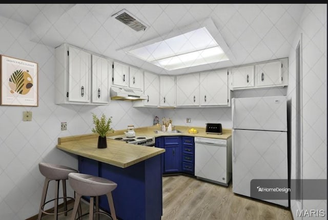 1380 Heritage Lndg Unit 105, Frontier Township, MO 63303 - kitchen with dishwasher, blue cabinetry, fridge, a peninsula, and under cabinet range hood