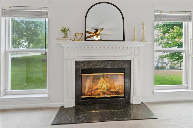 detailed view of a fireplace, a ceiling fan, carpet flooring, and baseboards