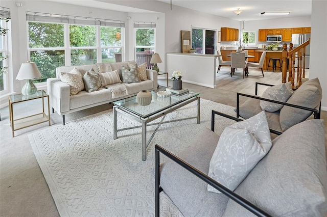 living room featuring light colored carpet, plenty of natural light, and baseboards