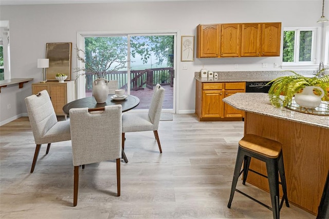 dining room featuring plenty of natural light, light wood finished floors, and baseboards