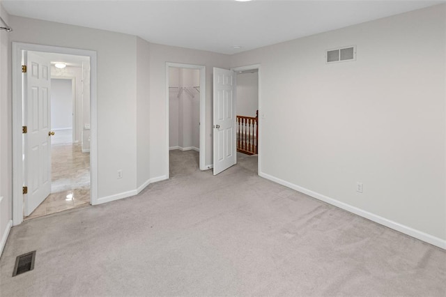 unfurnished bedroom with carpet, baseboards, a spacious closet, and a closet