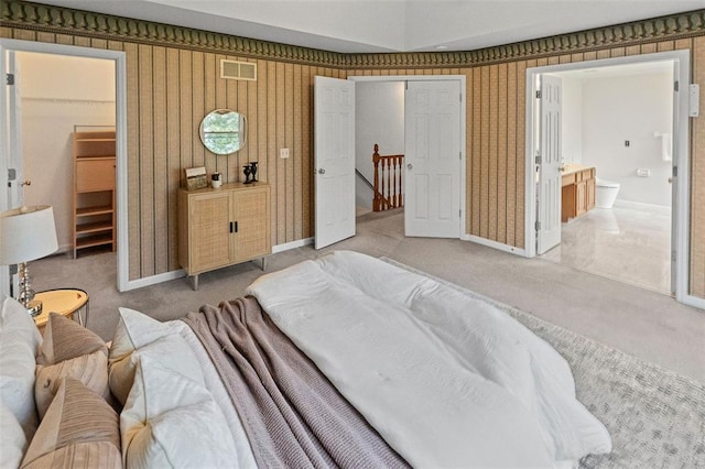 carpeted bedroom featuring baseboards and ensuite bath