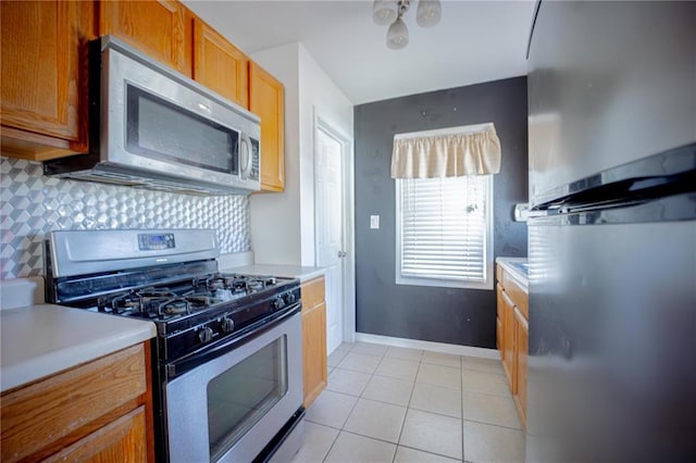 225 Haller Ave, East Alton, IL 62024 - kitchen featuring appliances with stainless steel finishes, light countertops, backsplash, light tile patterned flooring, and baseboards
