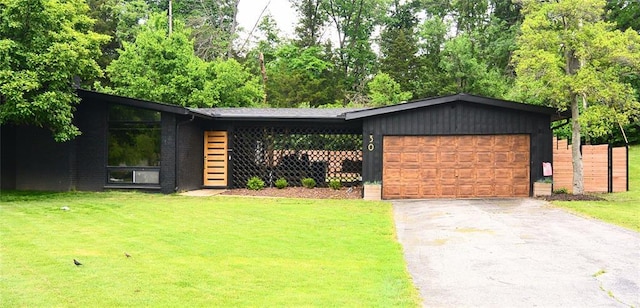 mid-century modern home with an attached garage, driveway, a front lawn, and brick siding