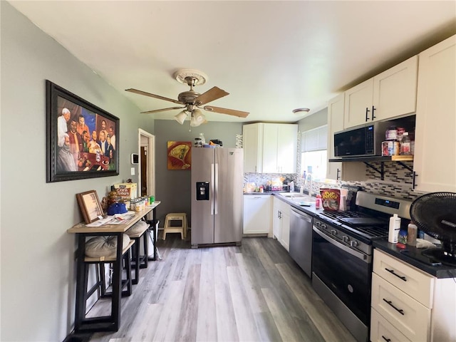 2515 Countess Dr, Saint Louis, MO 63136 - kitchen featuring stainless steel appliances, white cabinets, wood finished floors, and tasteful backsplash