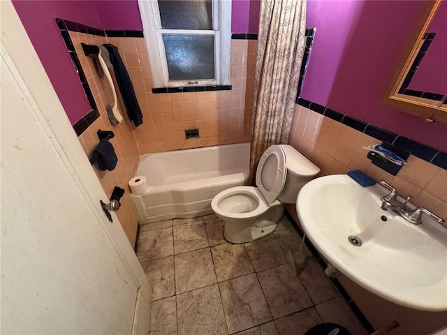 206 Thoroughman Ave, Ferguson, MO 63135 - bathroom featuring toilet, tile walls, a sink, shower / bath combination with curtain, and a wainscoted wall