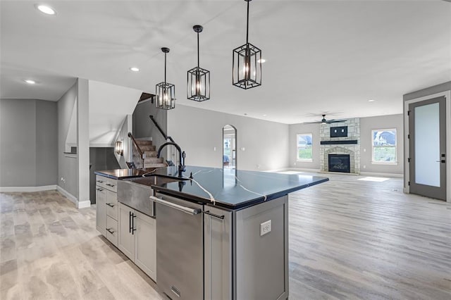 535 Crail Ct, Ofallon, MO 63368 - kitchen with dark countertops, a sink, dishwasher, light wood-type flooring, and a fireplace