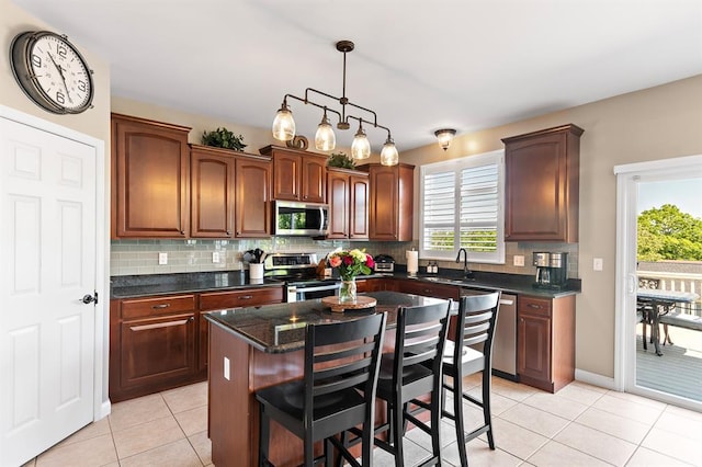 kitchen with stainless steel appliances, a sink, light tile patterned flooring, decorative backsplash, and a kitchen breakfast bar