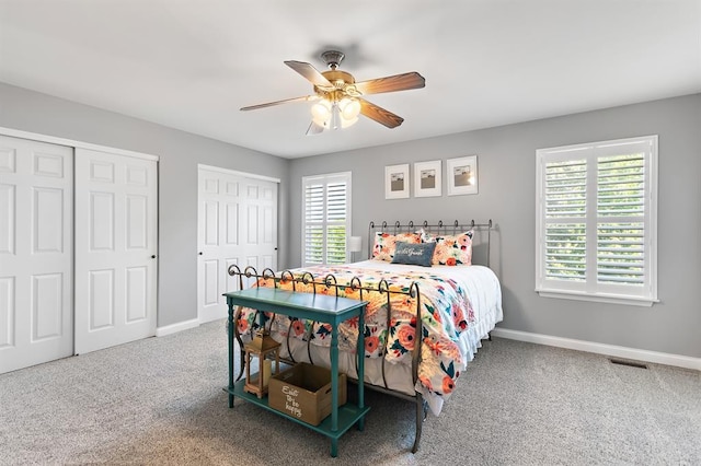 bedroom featuring carpet flooring, multiple closets, baseboards, and a ceiling fan