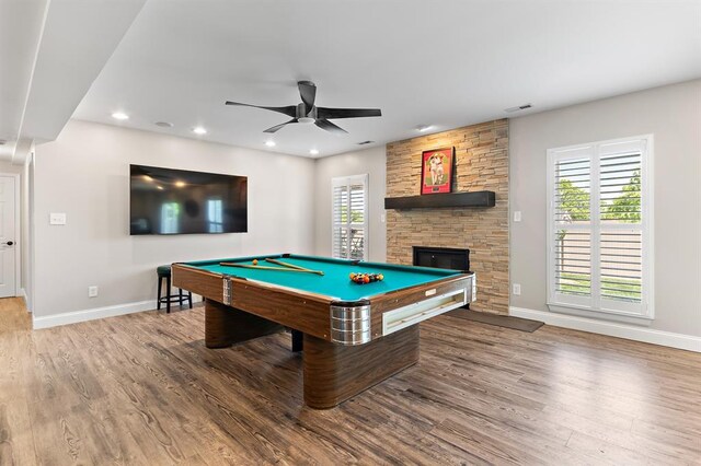 game room featuring ceiling fan, wood finished floors, baseboards, a stone fireplace, and recessed lighting