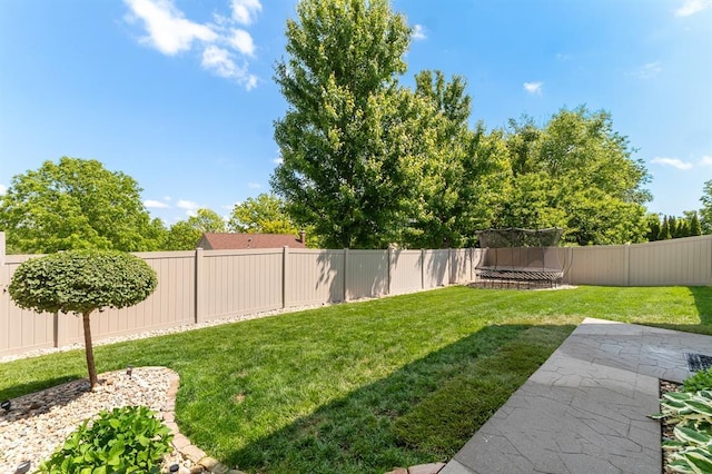 view of yard with a trampoline and a patio area