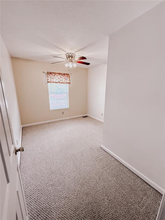 222 Elm Dr, Fairview Heights, IL 62208 - empty room with light colored carpet, a ceiling fan, baseboards, and a textured ceiling