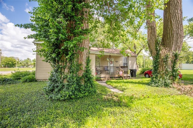 back of property with covered porch and a lawn
