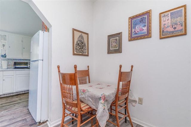 dining space featuring light wood-style flooring and baseboards