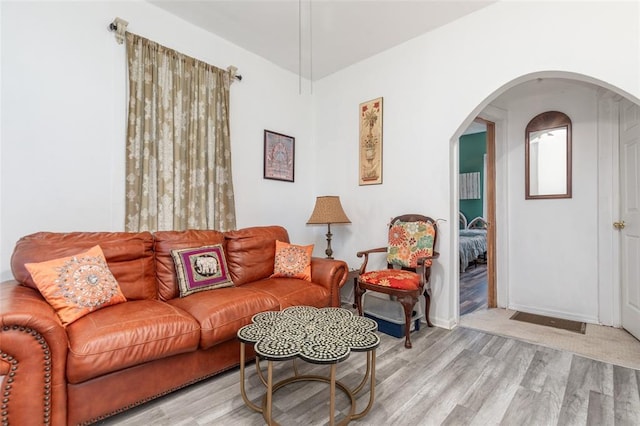 living area with wood finished floors, arched walkways, and baseboards