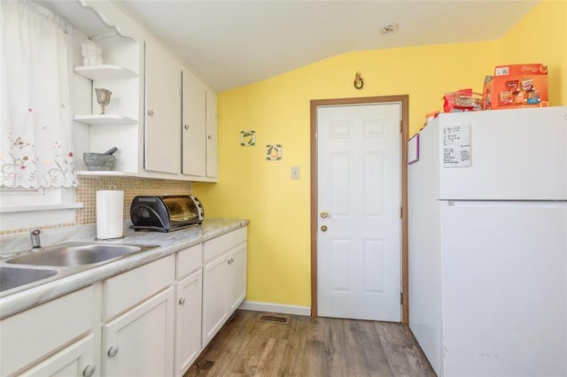 kitchen with freestanding refrigerator, vaulted ceiling, wood finished floors, open shelves, and white cabinets