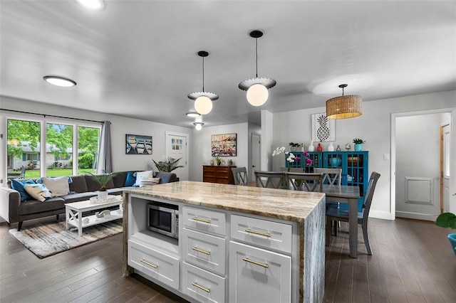 1719 Oak Hills St, Cape Girardeau, MO 63701 - kitchen featuring stainless steel microwave, dark wood-style floors, white cabinets, baseboards, and decorative light fixtures