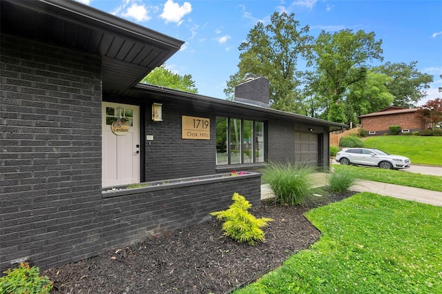 1719 Oak Hills St, Cape Girardeau, MO 63701 - view of front of house featuring brick siding, a chimney, a front yard, and an attached garage