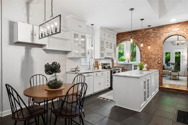 kitchen with white appliances, a sink, brick wall, glass insert cabinets, and white cabinets