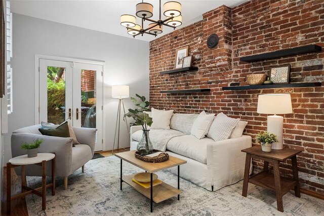 living room featuring a chandelier, brick wall, wood finished floors, and french doors