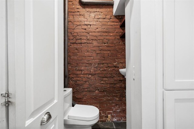 bathroom with brick wall and toilet