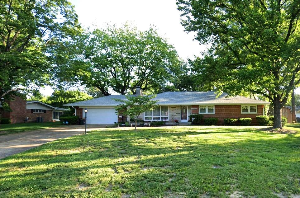 single story home with driveway, an attached garage, a front lawn, and brick siding