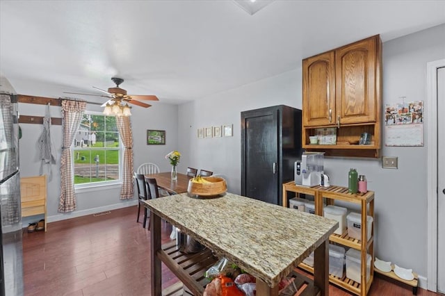 15 W 13th St, Washington, MO 63090 - kitchen with a ceiling fan, baseboards, dark wood-style flooring, a kitchen breakfast bar, and light stone counters