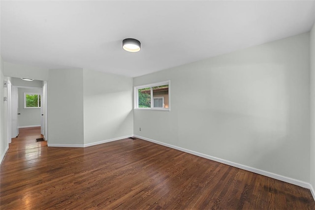 spare room featuring baseboards and wood finished floors