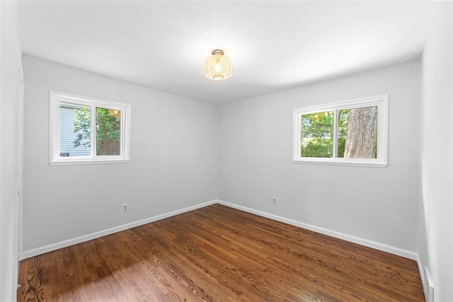 unfurnished room with baseboards and dark wood finished floors