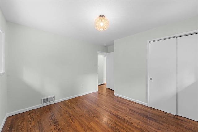 unfurnished bedroom featuring wood finished floors, baseboards, and a closet