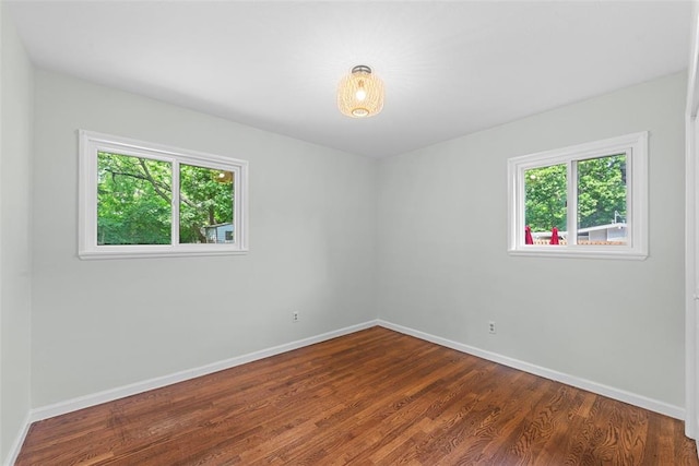 spare room featuring baseboards and dark wood-style flooring