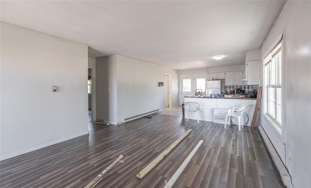 108 College Ave, Licking, MO 65542 - unfurnished living room with a baseboard heating unit, dark wood finished floors, and baseboards