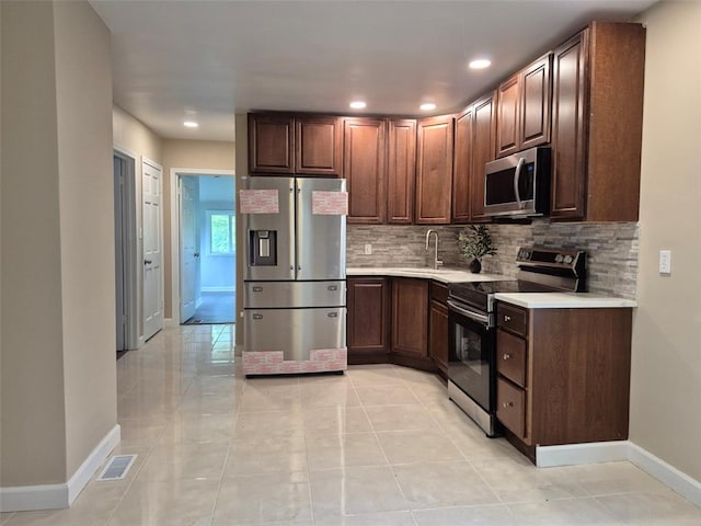 9643 Holtwood Rd, Overland, MO 63114 - kitchen with appliances with stainless steel finishes, baseboards, decorative backsplash, light countertops, and recessed lighting