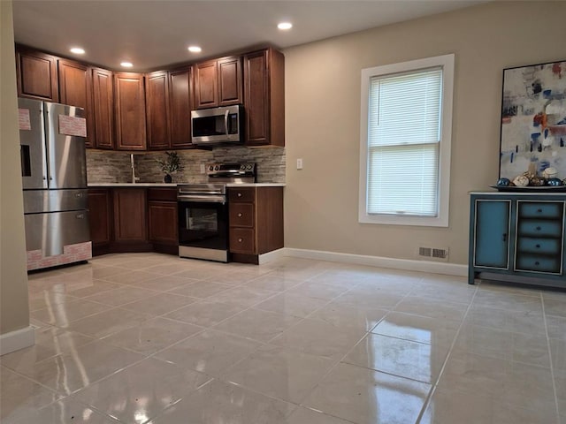 9643 Holtwood Rd, Overland, MO 63114 - kitchen featuring stainless steel appliances, tasteful backsplash, baseboards, light countertops, and light tile patterned floors