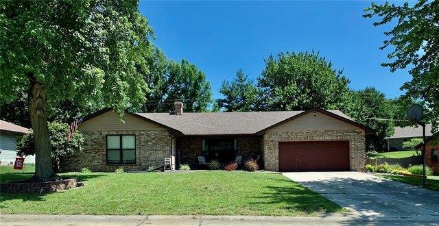 ranch-style home with an attached garage, driveway, a front lawn, and a chimney