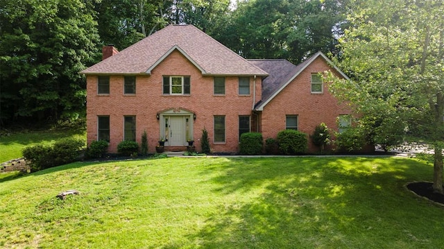 1711 El Rio Dr, Cape Girardeau, MO 63701 - colonial-style house featuring a chimney, a front lawn, brick siding, and a shingled roof