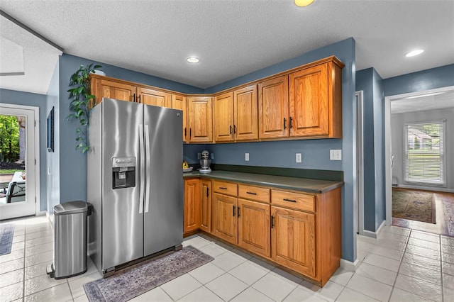 1711 El Rio Dr, Cape Girardeau, MO 63701 - kitchen with stainless steel fridge, healthy amount of natural light, dark countertops, brown cabinets, and a textured ceiling