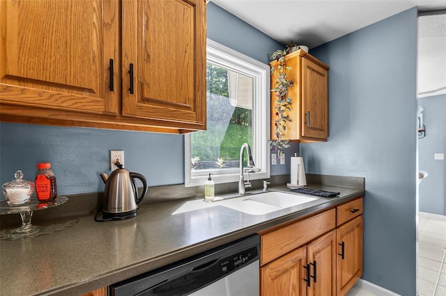 1711 El Rio Dr, Cape Girardeau, MO 63701 - kitchen with stainless steel dishwasher, dark countertops, a sink, brown cabinetry, and light tile patterned floors