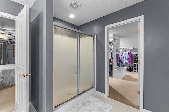 1711 El Rio Dr, Cape Girardeau, MO 63701 - ensuite bathroom with a shower stall, baseboards, a textured ceiling, tile patterned floors, and a spacious closet