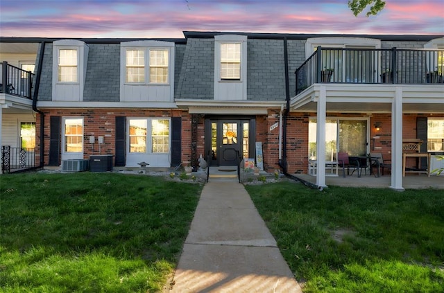 853 Dumont Pl Unit A, Saint Louis, MO 63125 - view of front facade featuring mansard roof, brick siding, a lawn, central AC, and a shingled roof